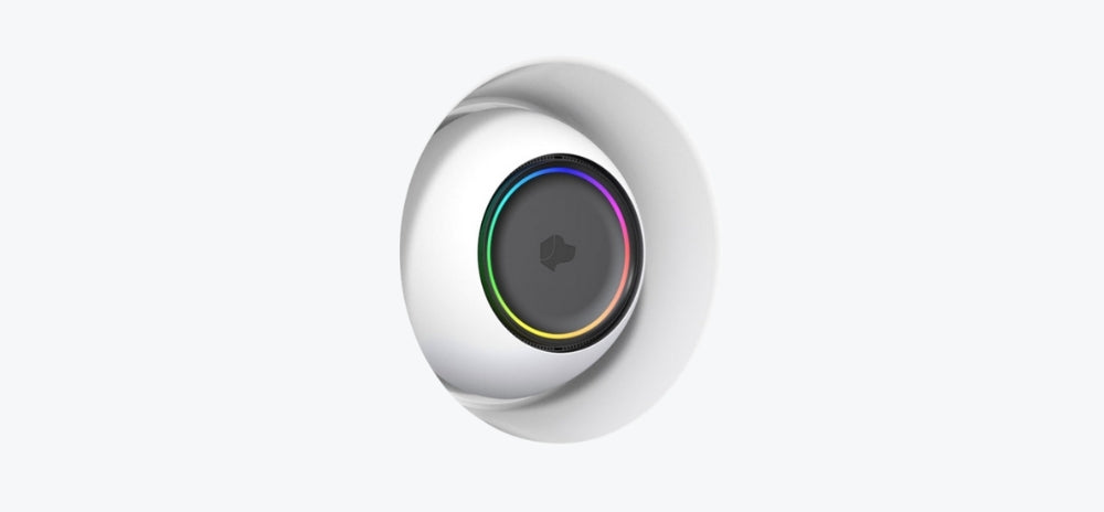 Josh.ai voice control device recessed into a SeeLess white in-wall mount, featuring a circular black face with a multicolour LED ring and smooth curved frame.