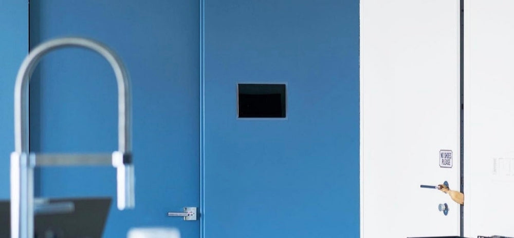 Flush-mounted Control4 touch panel integrated into a modern blue wall inside a contemporary home interior.