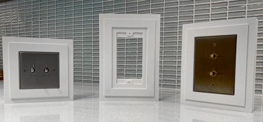 Meljac architectural-style keypads displayed in white flush in-wall mounts, featuring metallic finishes in silver and brass tones.