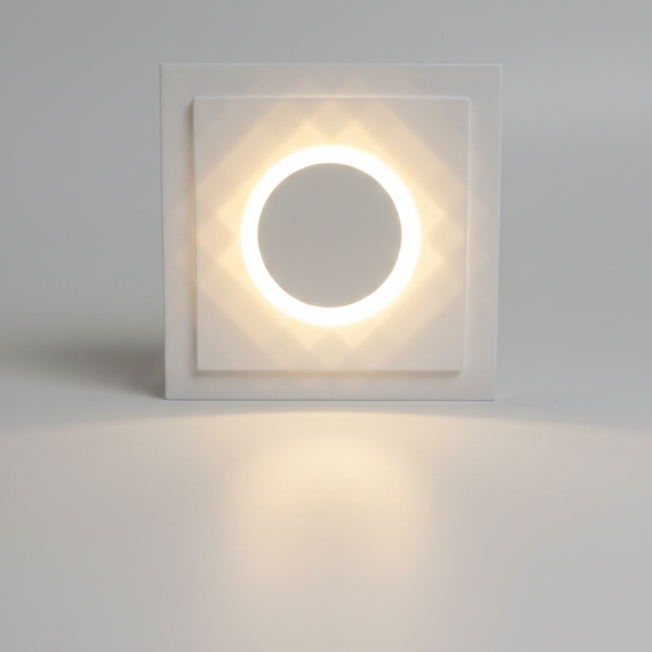A round white recessed light fixture with a glowing circular LED ring in the center, shown on a tabletop.