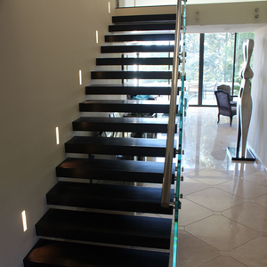 Straight view of a modern staircase with installed well-lit SeeLess step lights mounts.