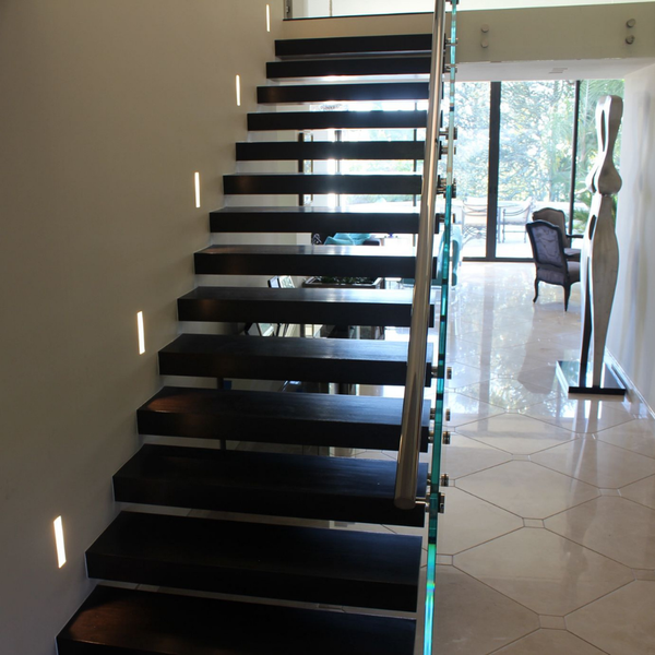 Straight view of a modern staircase with installed well-lit SeeLess step lights mounts.