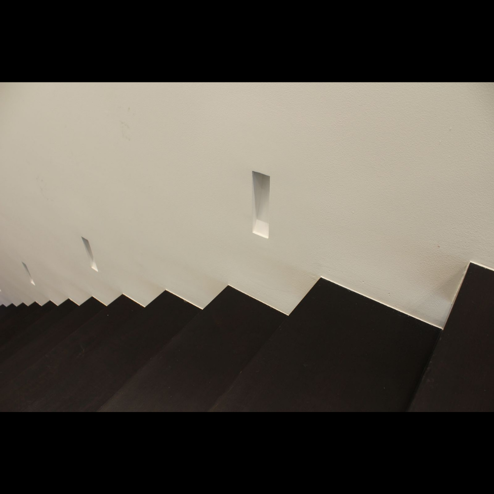 Wide shot of a modern staircase featuring unlit 9-inch SeeLess step light mounts unlit.