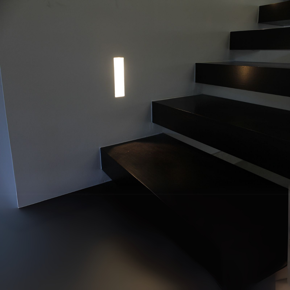 Modern staircase with a wall-mounted gypsum flush mount rectangular step light fixture in a minimalistic setting.